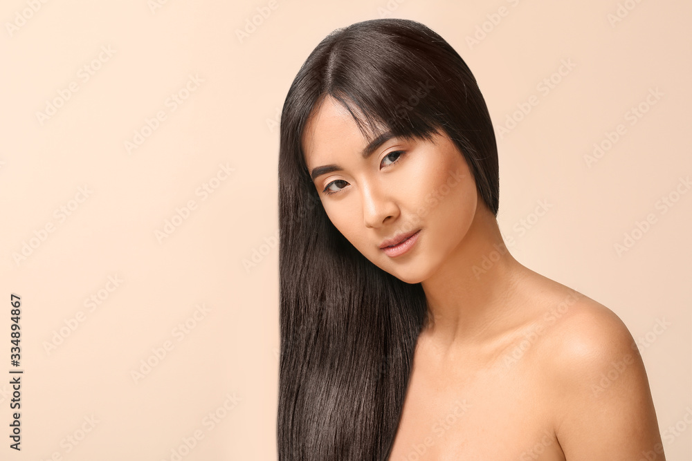 Young Asian woman with beautiful long hair on color background