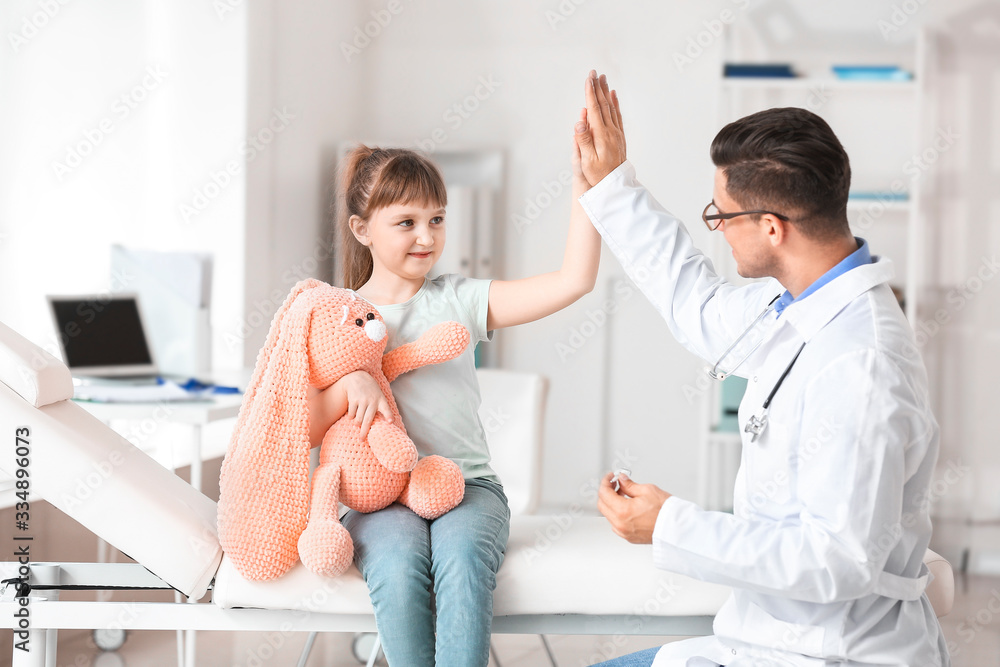 Pediatrician and little girl giving each other high-five in clinic