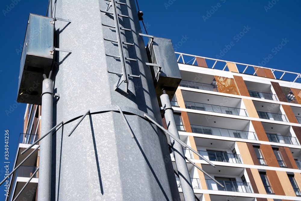 High voltage towers with electrical wires on apartment building background. 