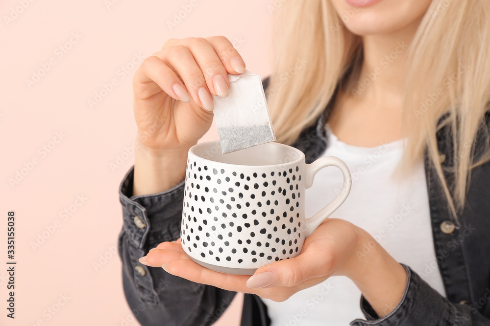 Beautiful young woman with tea on color background, closeup