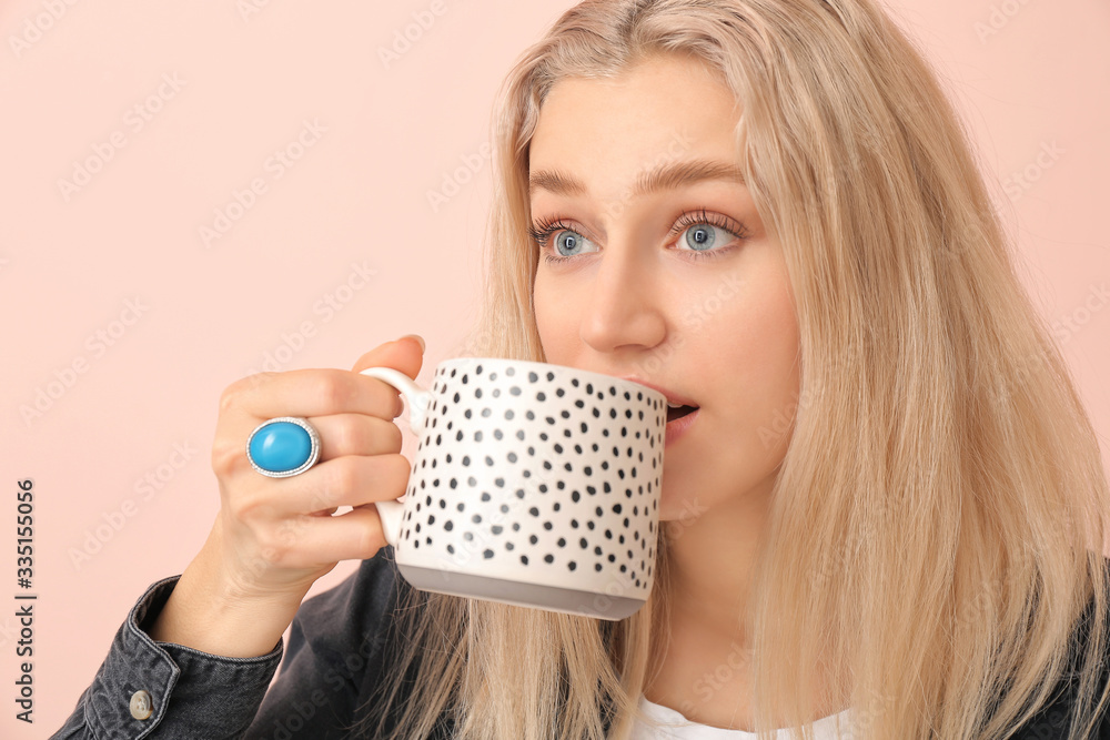 Beautiful young woman with tea on color background