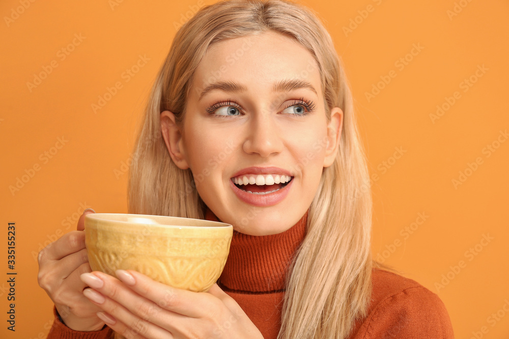 Beautiful young woman with tea on color background