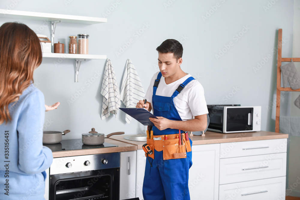 Housewife and worker repairing oven in kitchen