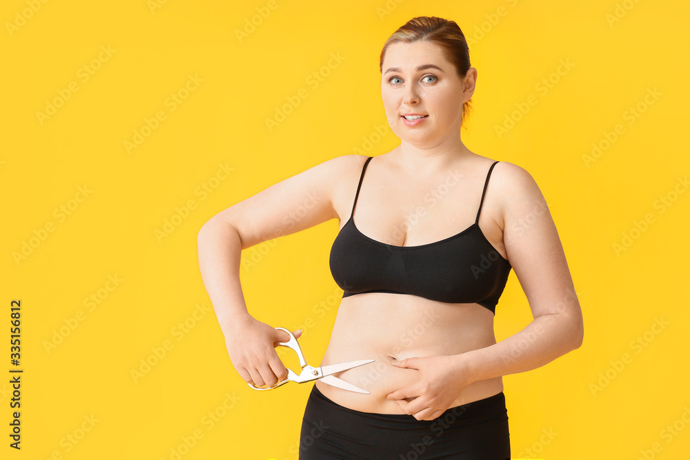 Overweight woman with scissors on color background. Weight loss concept