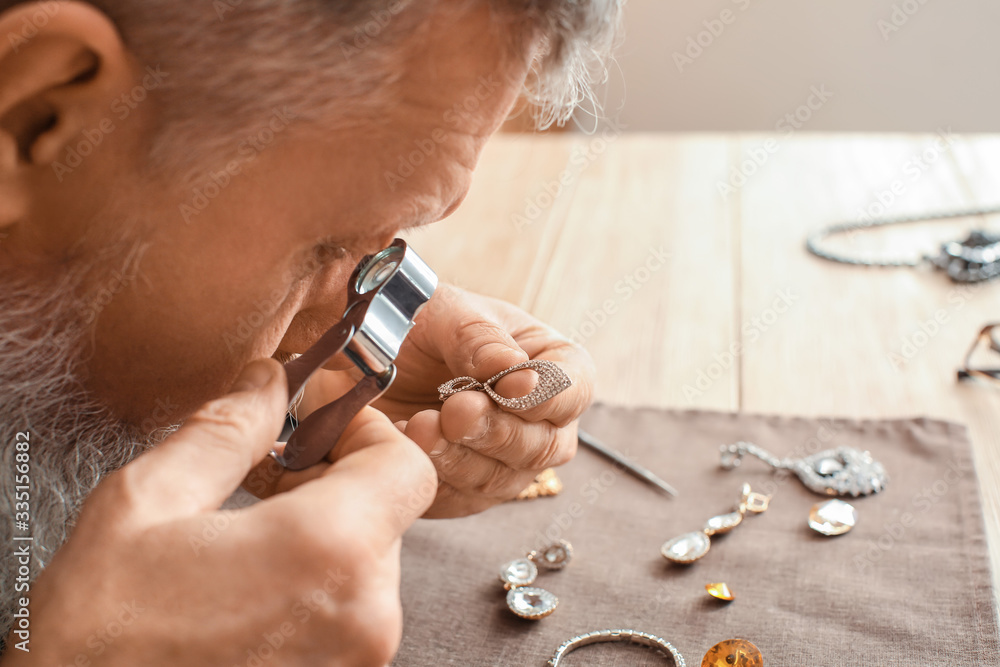 Jeweller examining adornment in workshop, closeup