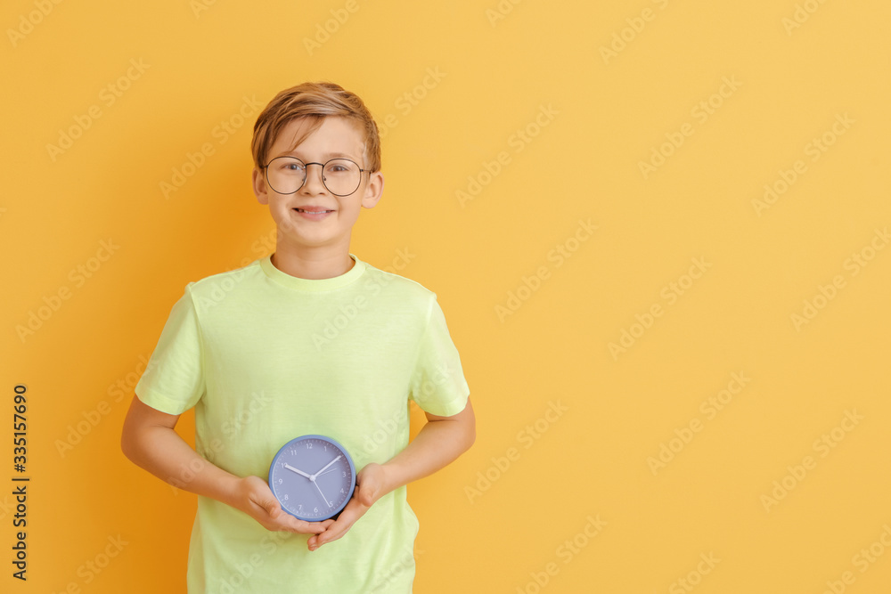 Little boy with alarm clock on color background