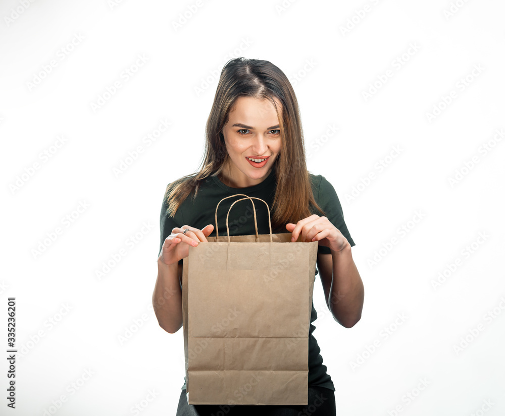 Woman holding grocery shopping bag on white background. Young girl is looking into light brown shopp