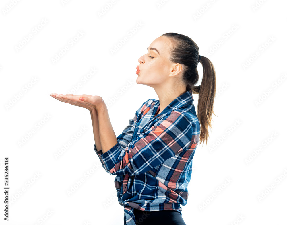 Cute girl sends a kiss. Adorable young girl holds hands near lips in kiss sign. Checkered shirt, pho