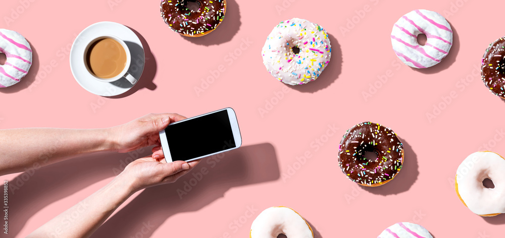 Person using a smartphone with donuts from above