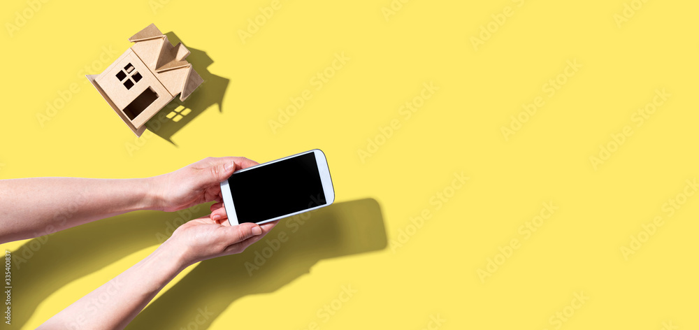 Person using a smartphone with a miniature house from above