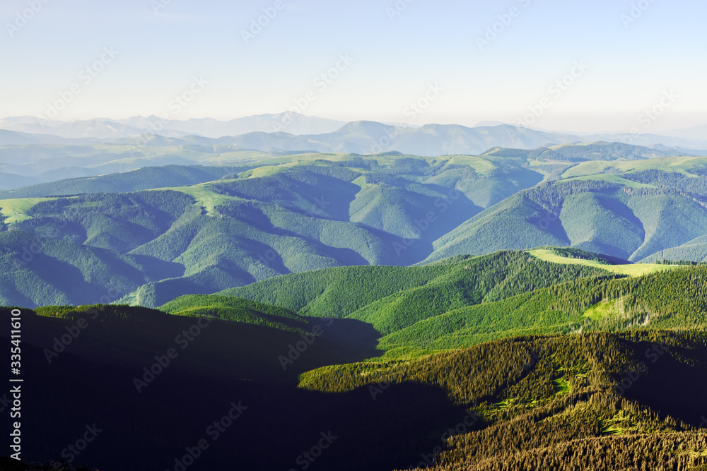 Green mountains range in summer time. Breathtaking view on hills covered by lush forest. Landscape p