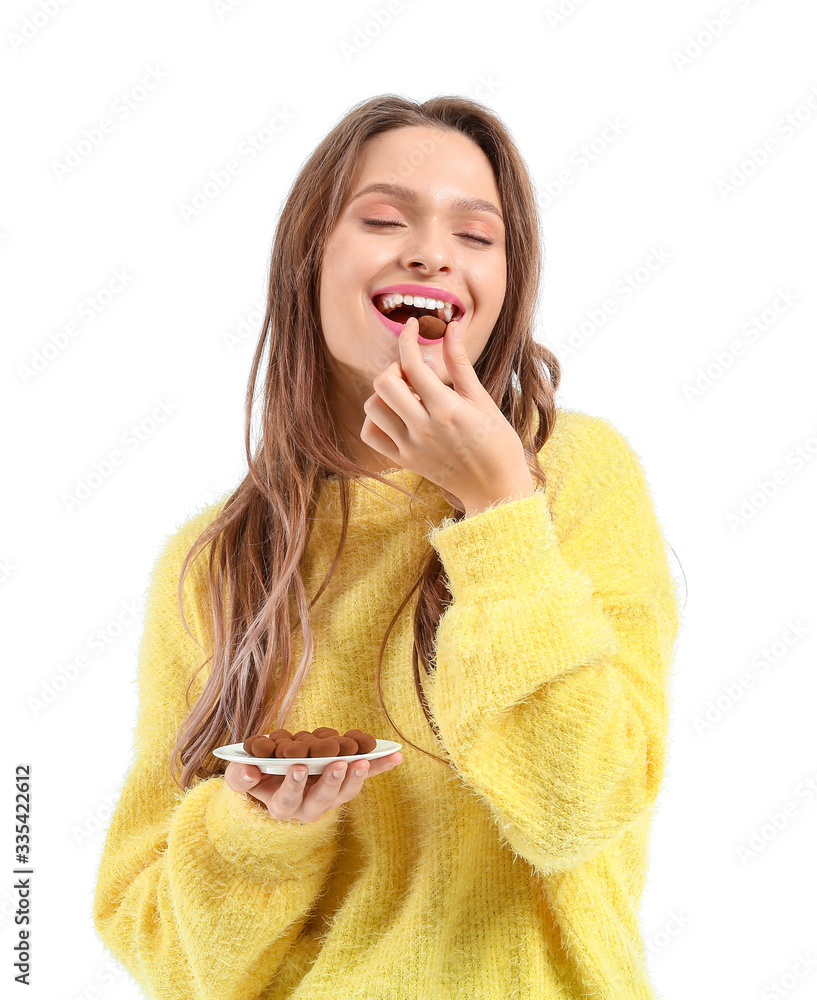 Beautiful young woman with chocolate candies on white background