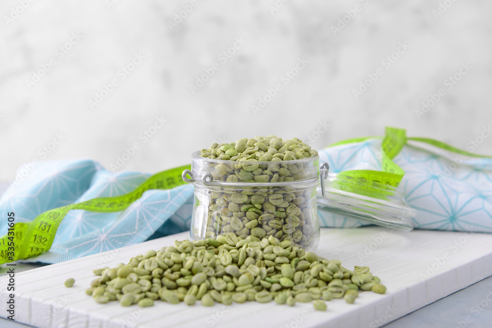 Jar with green coffee beans on table