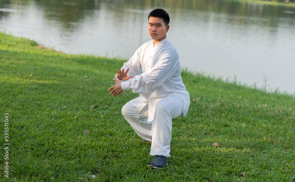 Young healthy sports man workout Tai Chi Chuan, Tai Ji and QI gong in the park for healthy, traditio