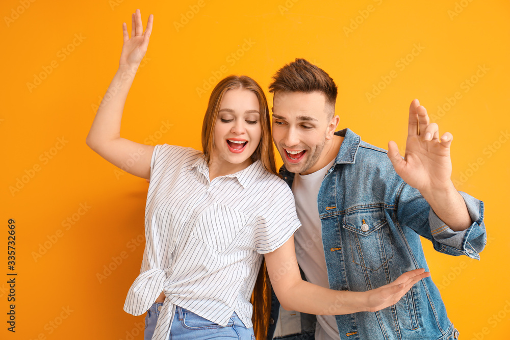 Happy young couple dancing against color background