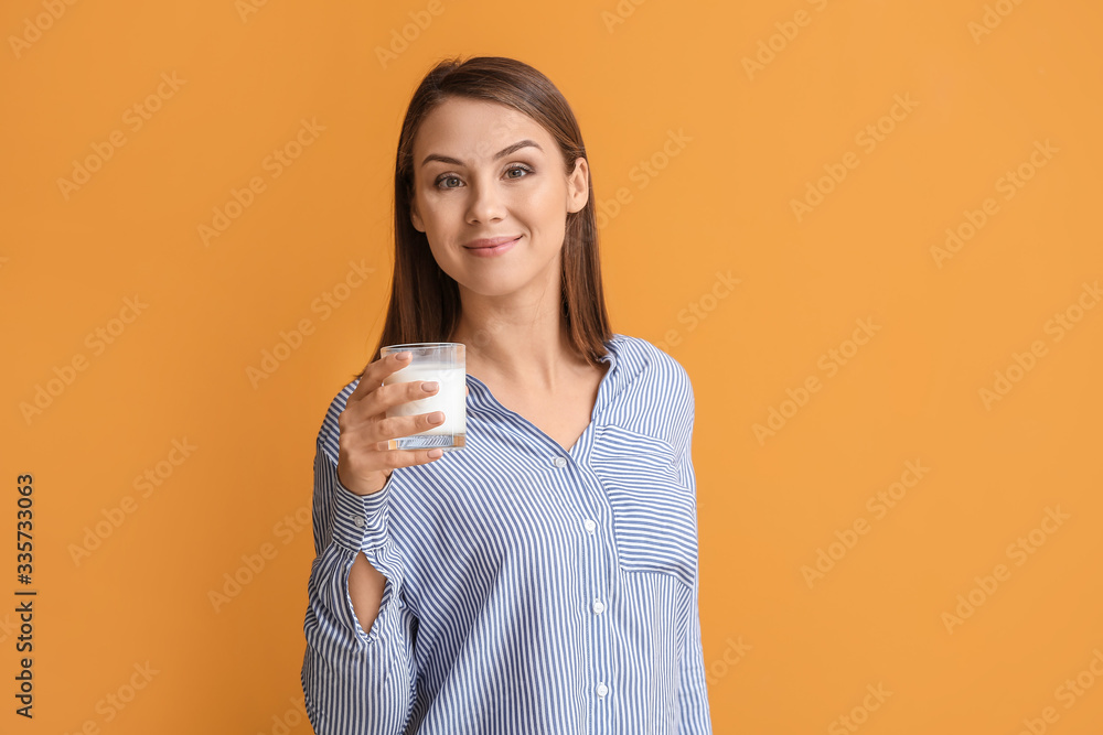 Beautiful young woman with glass of milk on color background