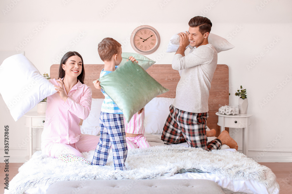 Happy family fighting on pillows in bedroom at home