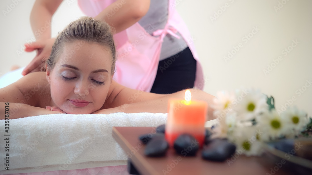 Relaxed woman getting back massage in luxury spa with professional massage therapist. Wellness, heal