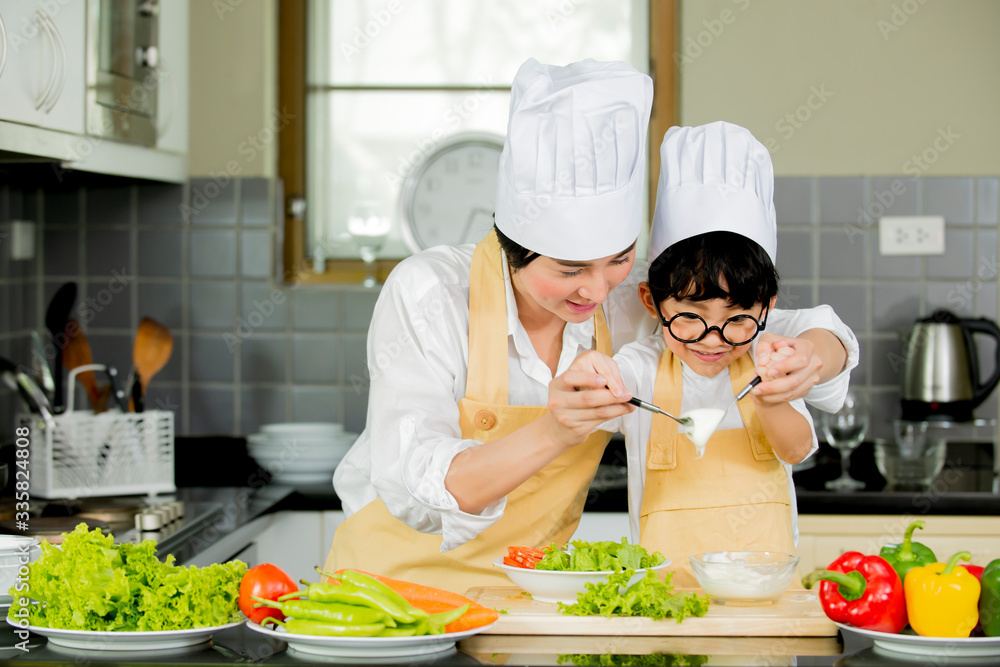 Happy  Cute asian little boy with mother  preparing cooking fresh salad in kitchen at home