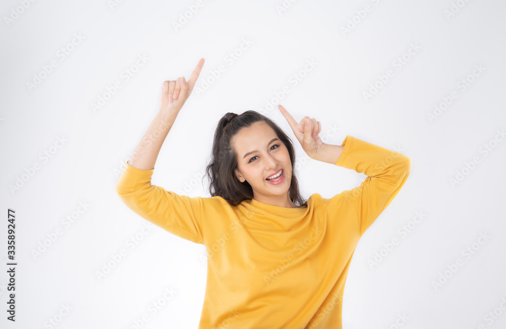 Young happy Asian woman pointing finger hands up to copy space  she wearing yellow sweater shirt sho