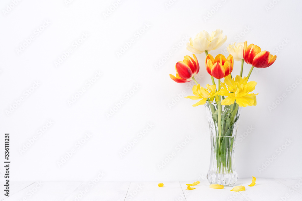 Tulip flower in glass vase with picture frame place on white wooden table background against clean w