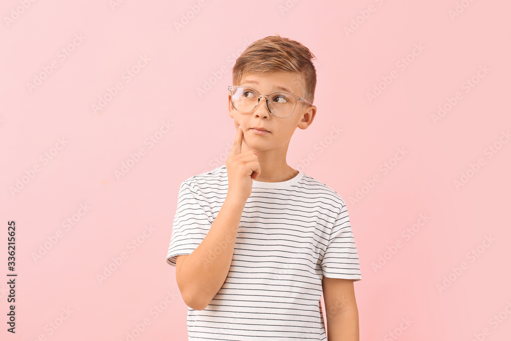 Thoughtful little boy with eyeglasses on color background