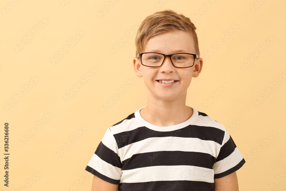 Cute little boy with eyeglasses on color background