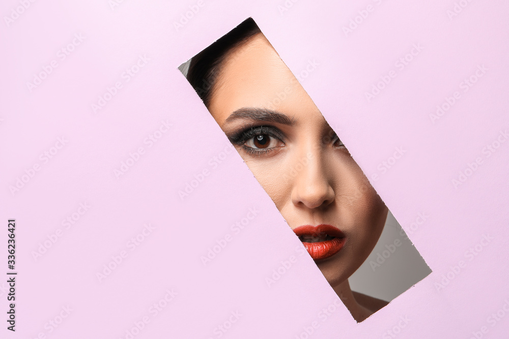 Beautiful young woman visible through cut color paper