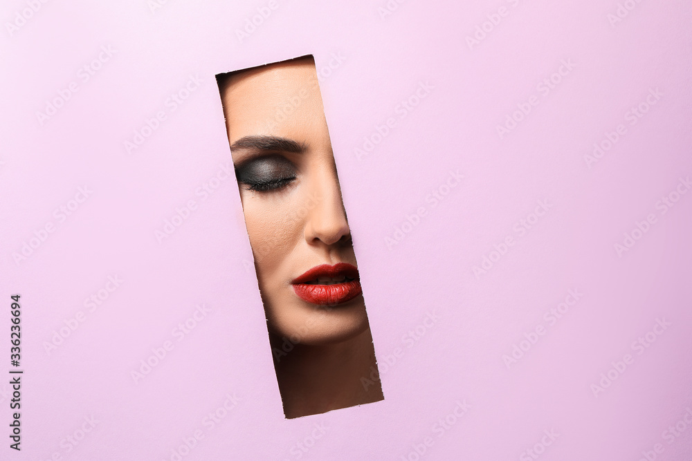 Beautiful young woman visible through cut color paper