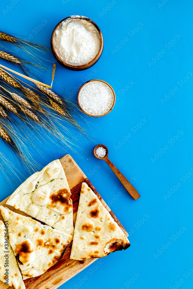 Focaccia ingredients. Wheat ears, flour, oil near bread on blue background top-down copy space