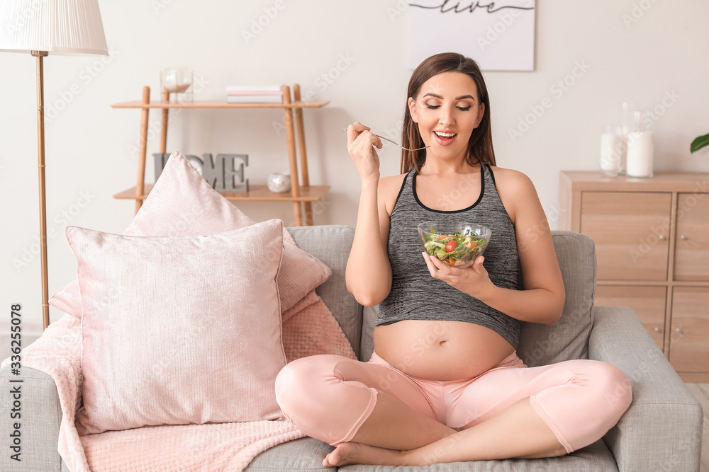 Beautiful pregnant woman eating healthy salad at home