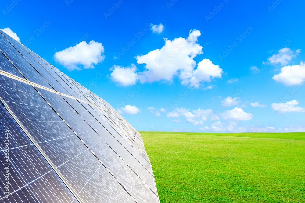 Photovoltaic solar panels and green grass on sky background,green clean alternative energy concept.