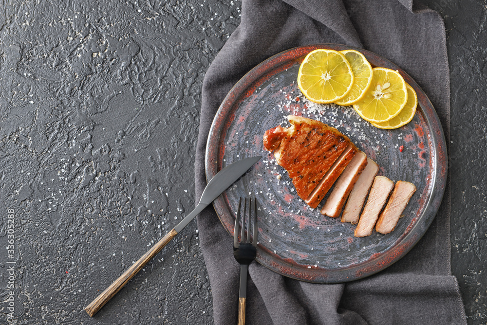 Plate with cooked pork steak on dark background