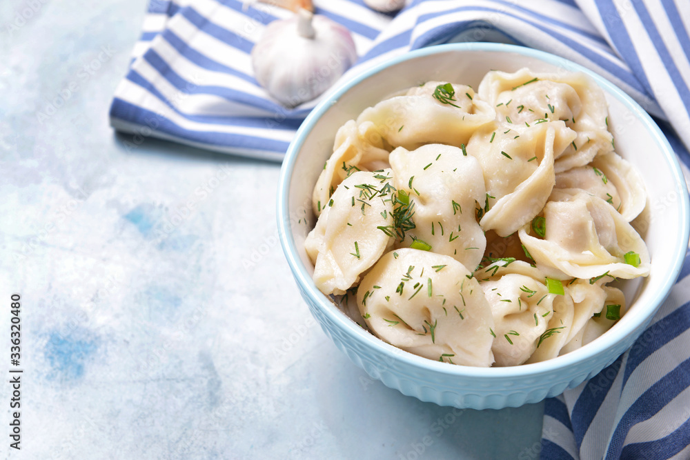 Bowl with tasty dumplings on color background