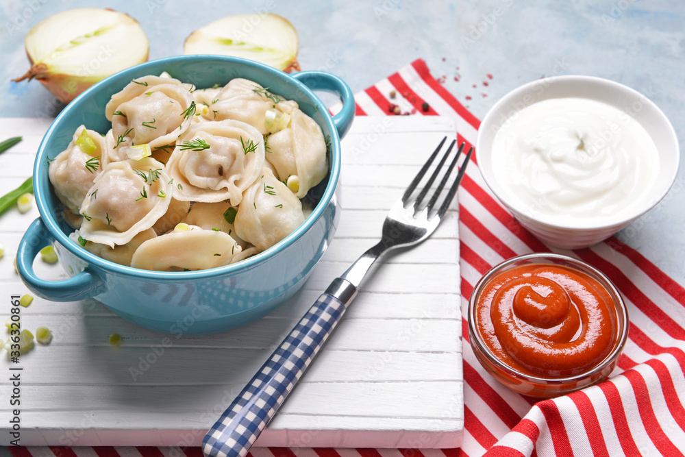 Pot with tasty dumplings and sauces on table