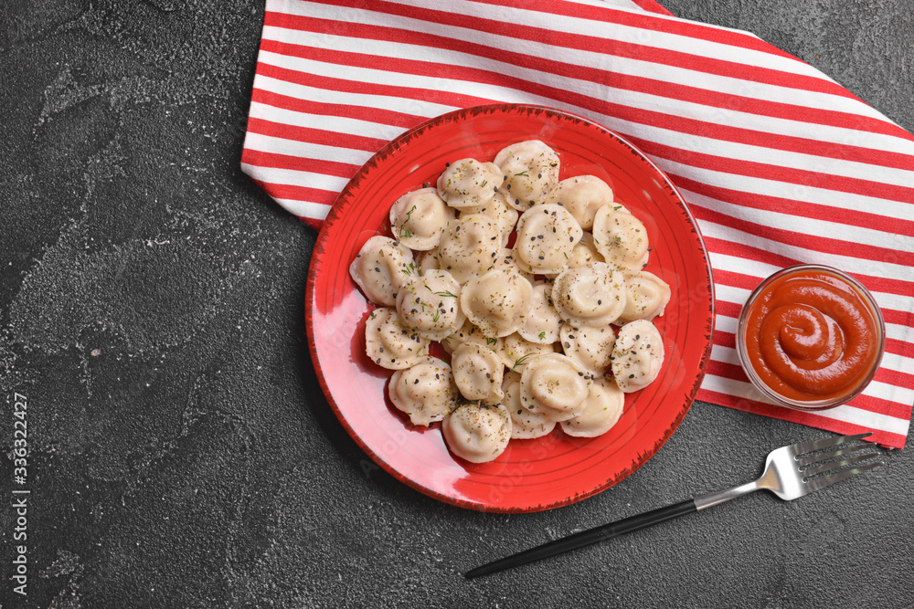 Plate with tasty dumplings and sauce on dark background