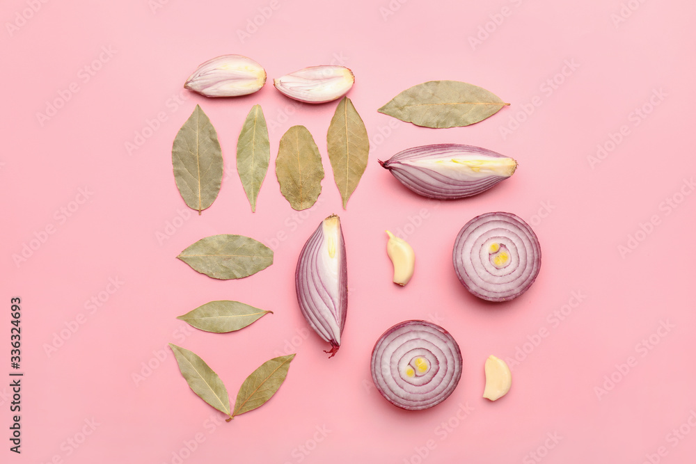 Pieces of fresh raw onion with garlic and bay leaves on color background