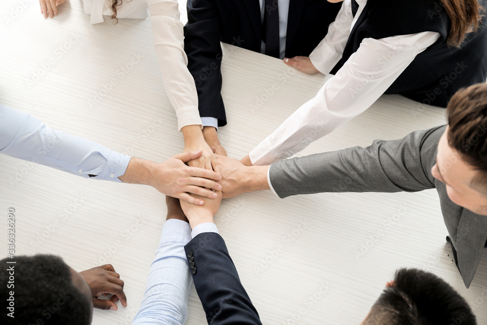 Group of business people putting hands together in office, top view. Unity concept