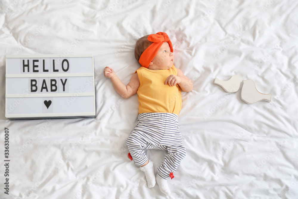 Stylish little baby girl lying on bed