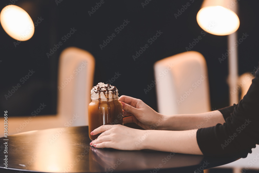 一个女人拿着一罐美味的冰咖啡坐在咖啡馆的桌子旁