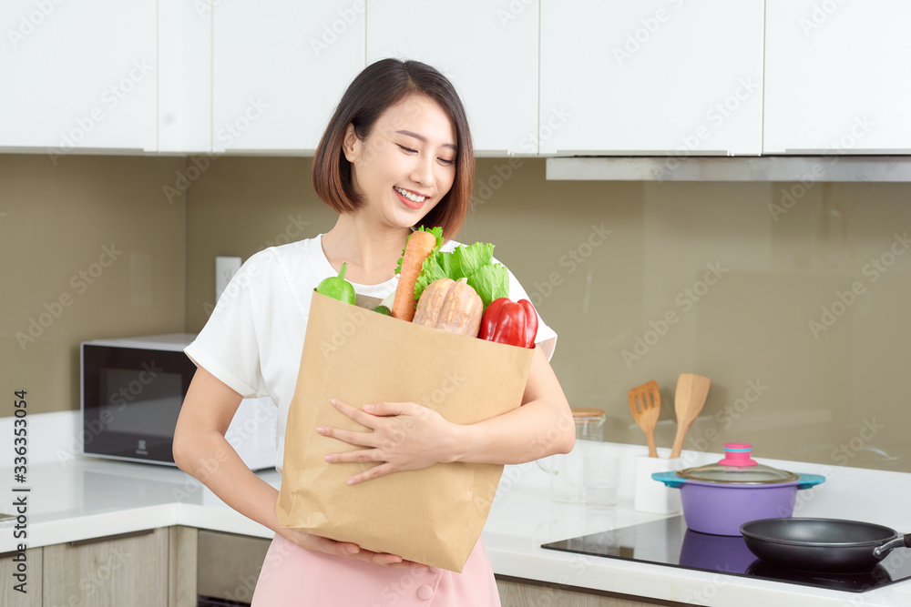 快乐的年轻亚洲女人，购物袋里有蔬菜。饮食理念。