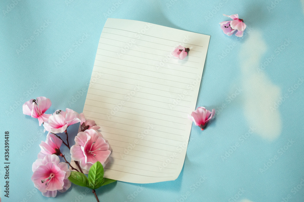 Top view of blank paper and flower bouquet on blue background, copy space