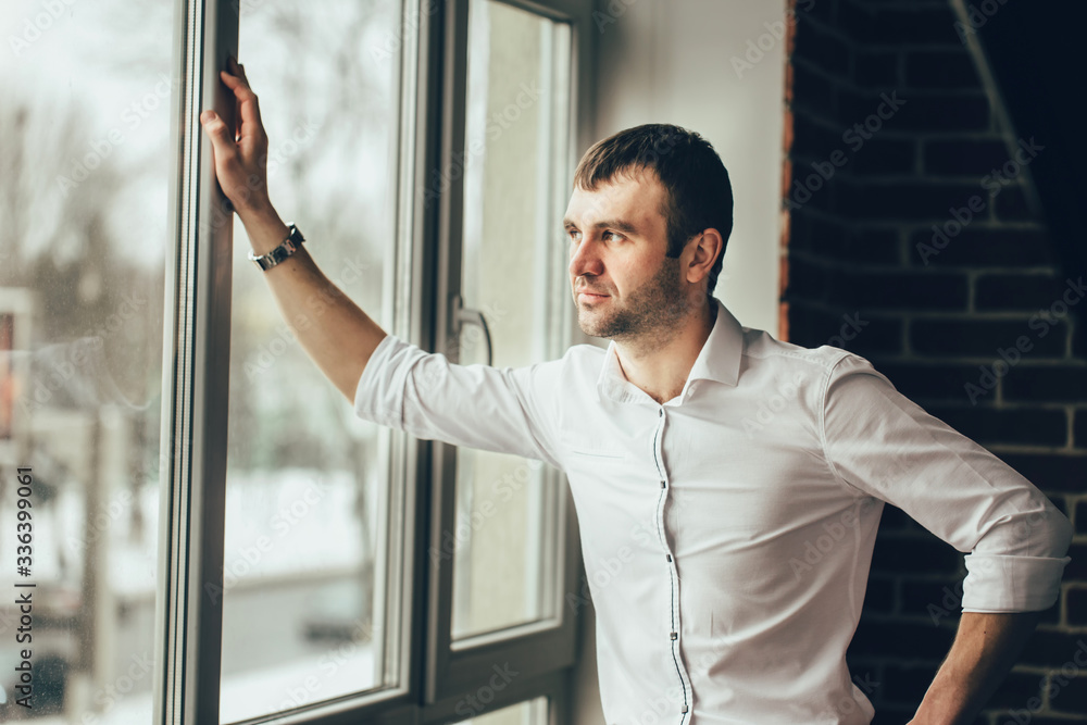 The man standing near the panoramic window. Hand on window. Stay at home during quarrantine.