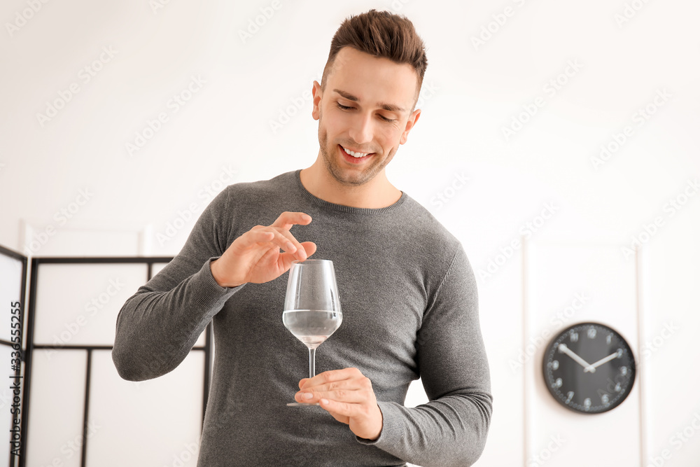 Young man playing music on glass with water at home