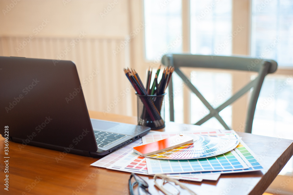 Working from home. Color swatch with a laptop on the office desk of the designer.