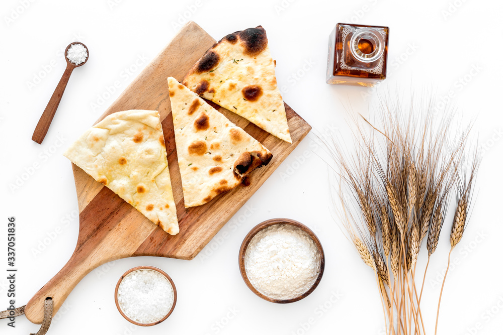 Focaccia ingredients. Wheat ears, flour, oil near bread on white background top-down