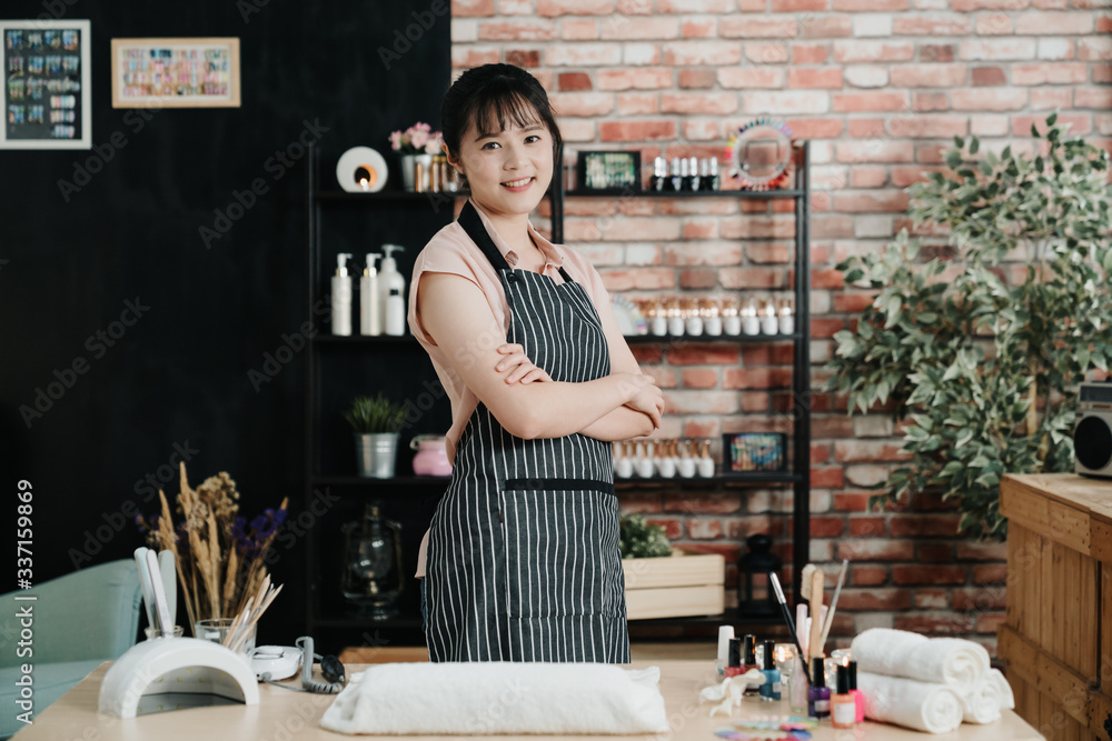 美丽的年轻亚洲中国女性美甲师站在美甲店前微笑的肖像