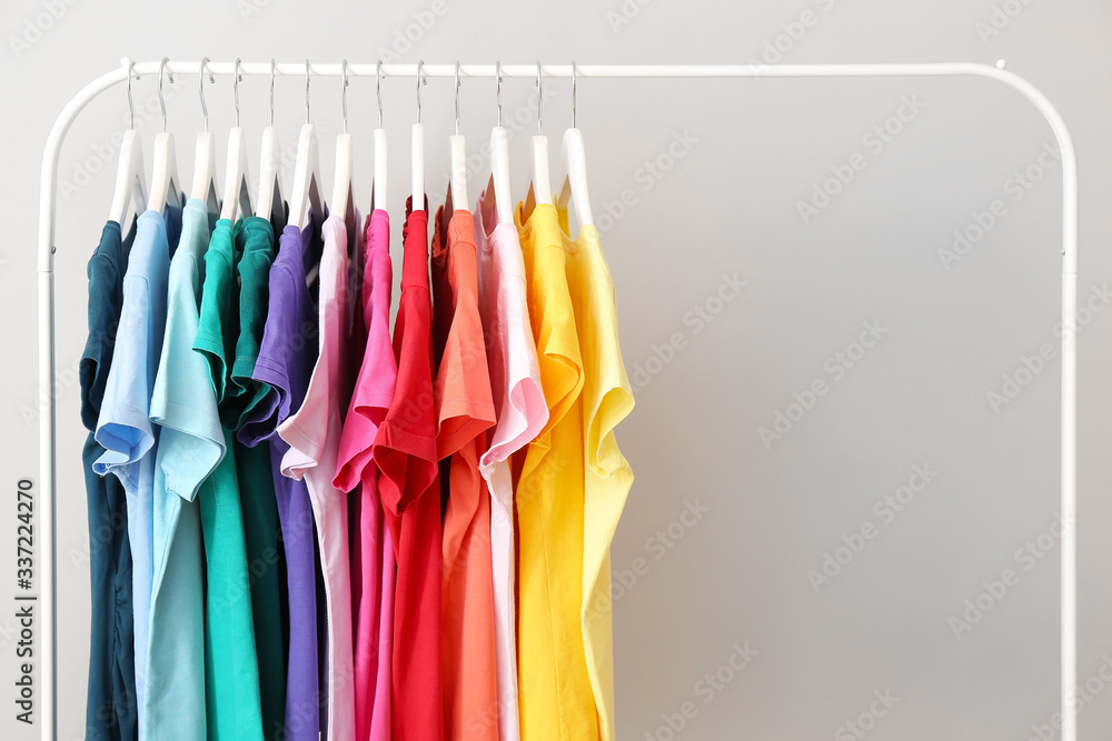 Rack with hanging clothes on grey background