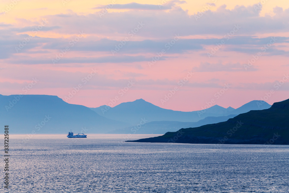 丹麦法罗群岛美丽的夏日日落。沿海水域孤独的船。风景如画