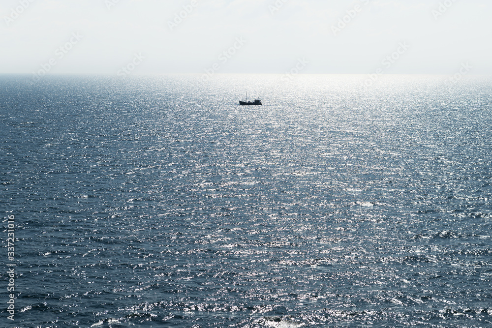 Lonely fishing ship trawler boat on ocean water. Calm clear sea sunny weather. Beautiful horizon of 